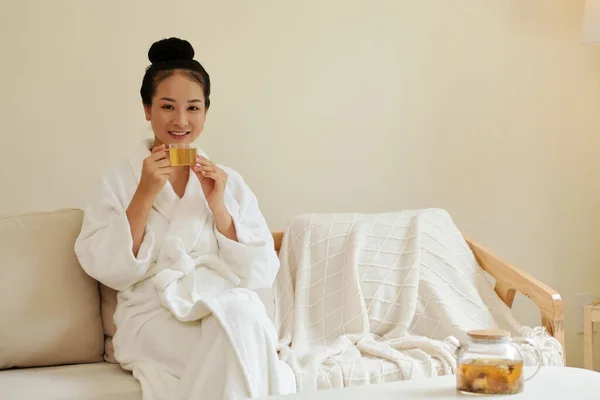 入浴後にソファで休んでハーブティーを飲む若いアジア人女性の肖像画 — ストック写真