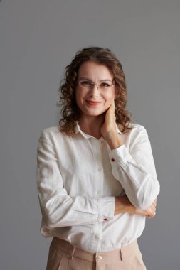 Gözlüklü, gülümseyen olgun bir kadının portresi. Yüzüne dokunuyor ve Comea 'ya bakıyor.