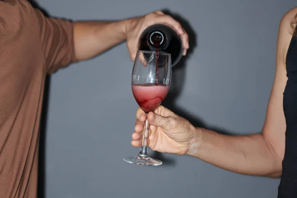 男人在女友的酒杯中倒入玫瑰晶莹的酒水 — 图库照片