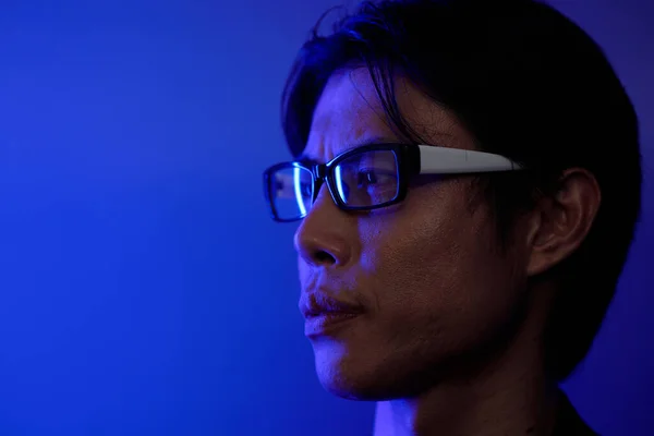 Gözlüklü Ciddi Bir Adamın Mavi Işıkta Dikilip Bakışlarını Kaçırması — Stok fotoğraf