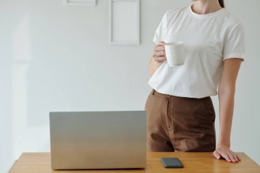 Laptop 'a yeni başvuru yüklenirken kahve içen genç kadın