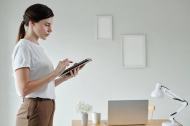 Genç iş kadını sekme bilgisayarından belgeyi kontrol ediyor