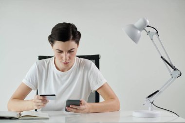 Mobil uygulamalarda düzen için oynarken kredi kartı kullanan genç bir kadın