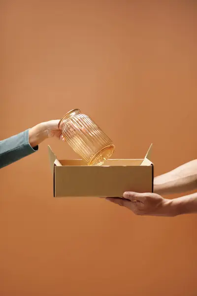 顾客的手把易碎的花瓶从盒子里拿出来 交给推销员 — 图库照片
