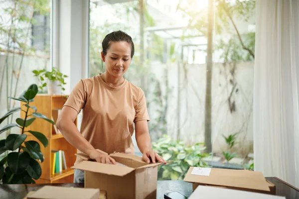 Woman opening boxes with belongings in new house she moved in