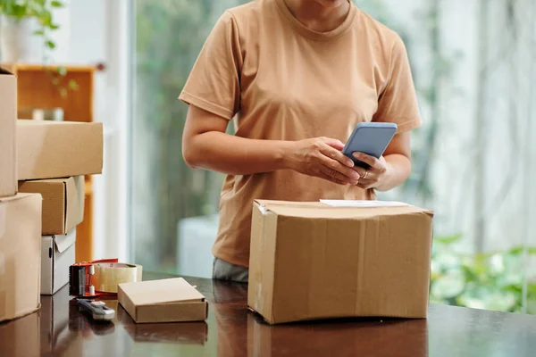 Woman scanning code on parcel before shipping it to customer