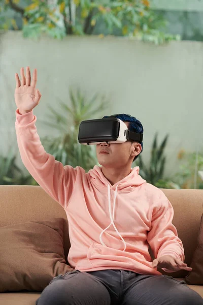 stock image Young man in pink hoodie playing videogame in VR headset