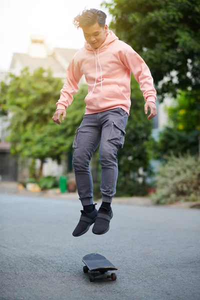Active young man performing stunt, jumping on skateboard
