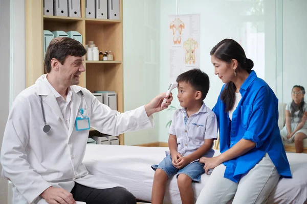Uśmiechnięty Lekarz Mierzący Temperaturę Ciała Małego Chłopca Termometrem Podczerwień — Zdjęcie stockowe