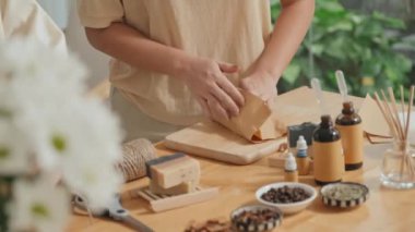 Tanımlanamayan iki kadının el yapımı sabunları ahşap masaya yapıştırdığı el yapımı kağıt.