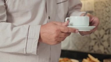 Evde pijamalı, neşeli, son sınıf öğrencisinin taze kahve karıştırıp koklayarak ve gülümseyerek gülümsediği bir sahne.