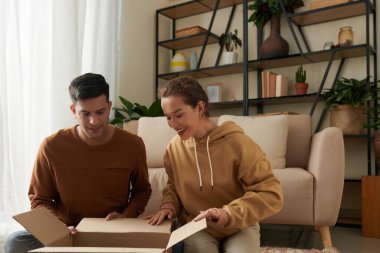 Heyecanlı genç çift internetten sipariş ettikleri ayakkabı ve kıyafetlerle büyük bir karton kutu açıyor.