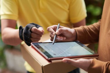 Paket alındıktan sonra genç adamın belgeyi tablet bilgisayarda imzalarken yakın plan resmi