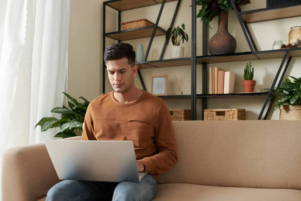 Frowning Young Man Sitting Couch Home Coding Answering Mails Laptop — Stock Photo, Image