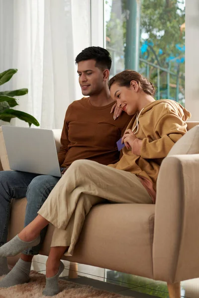 恋爱中的年轻夫妇坐在家里的沙发上 为网上观看他们喜爱的节目支付流媒体服务费 — 图库照片