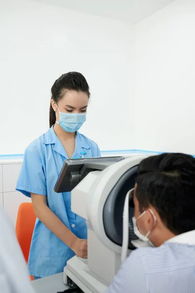 Серьёзная Медсестра Офтальмолог Устанавливает Рефрактометр Проверки Зрения Пациента — стоковое фото
