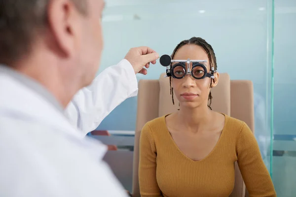 眼科医は 女性患者が試験枠をつけるのを助ける — ストック写真