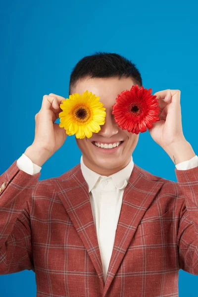 Portret Szczęśliwego Młodzieńca Trzymającego Przed Oczami Czerwone Żółte Gerbera Daisy — Zdjęcie stockowe