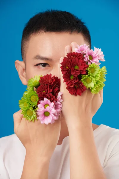 Ernstige Jongeman Bedekken Gezicht Met Handen Met Kleurrijke Bloeiende Bloemen — Stockfoto