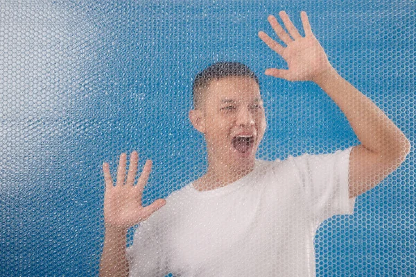 Umutsuz Genç Adam Baloncuklu Paket Duvarının Arkasında Bağırıyor — Stok fotoğraf