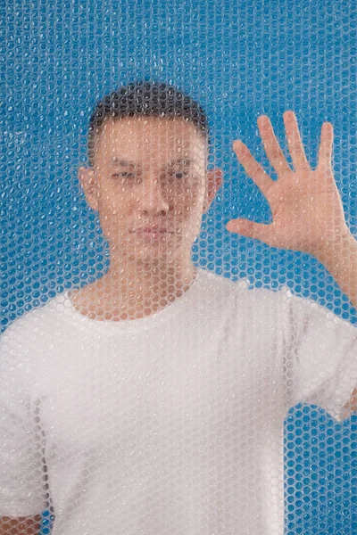 バブルラップの後ろに立つアジア人男性の肖像画と手で拭く — ストック写真