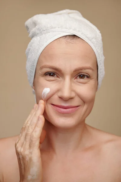 晚浴后使用保湿乳液的中年妇女的脸部 — 图库照片