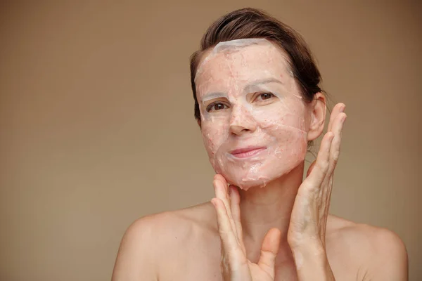 シャワー後の顔に毎日ケアシートマスクを適用肯定的な中年女性 — ストック写真