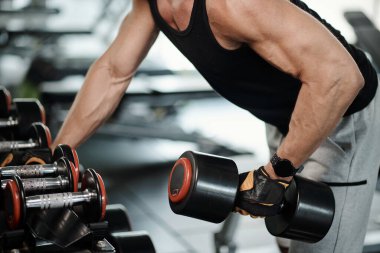 Formda adam üst gövde üzerinde çalışırken ağır dambıllar kaldırıyor.