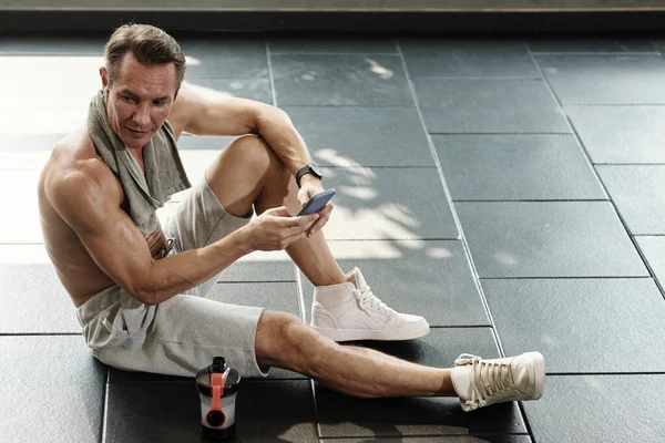 Mann Nach Morgendlichem Training Müde Boden Sitzend Und Smartphone Checkend — Stockfoto