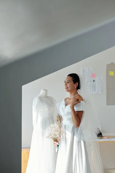 花の花束とサロンに立って白いウェディングドレスで楽しい美しい花嫁 — ストック写真
