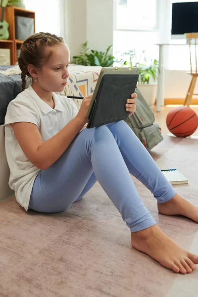 十几岁以下的女孩坐在卧室的地板上 在平板电脑的练习本上锻炼 — 图库照片
