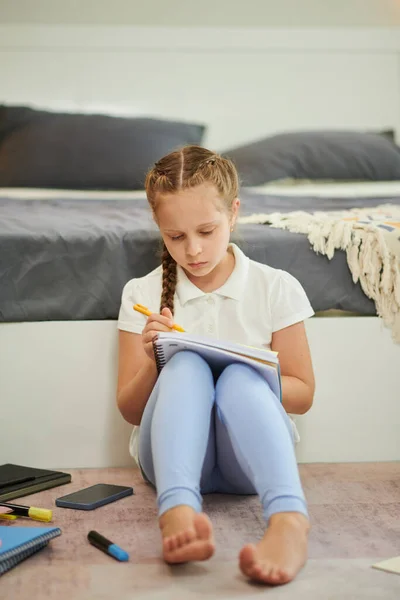 Ernste Preteen Mädchen Sitzt Auf Dem Boden Und Schreibt Essay — Stockfoto