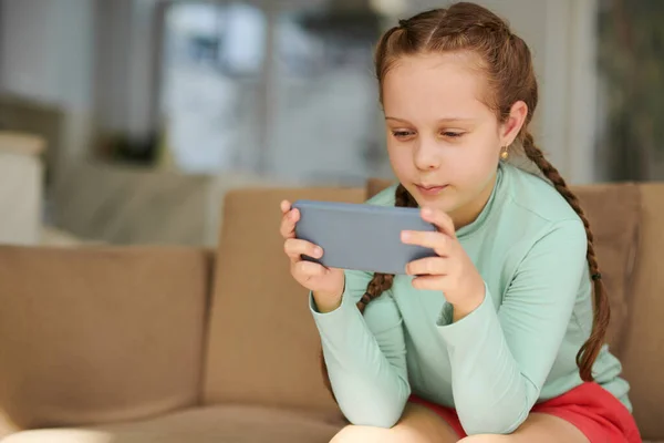 在智能手机上玩游戏或观看娱乐性视频的快乐女孩 — 图库照片