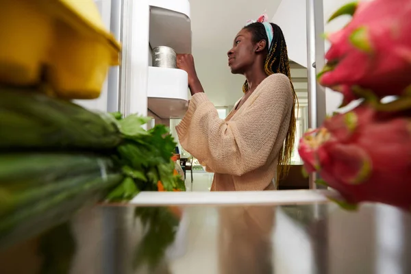 年轻女子从冰箱里拿出罐头食品做饭 — 图库照片