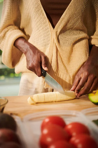 女人切香蕉加入粥或意大利面碗 — 图库照片