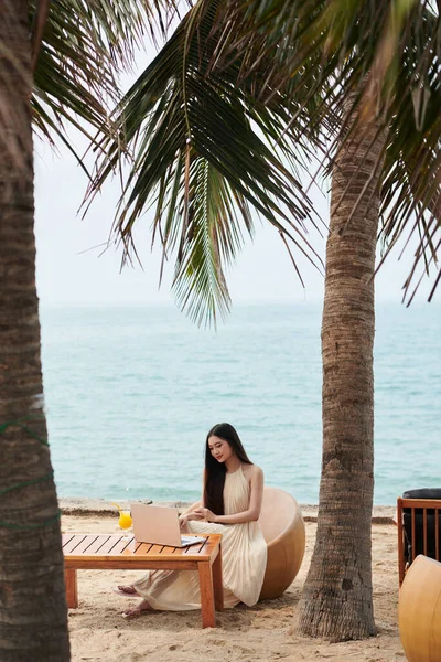 Tropikal Sahildeki Masada Çalışan Yazlık Elbiseli Genç Bir Kadın — Stok fotoğraf