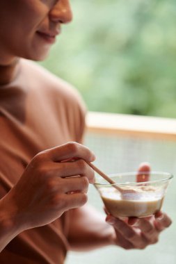 Gülümseyen genç adam kahvaltıda mısır gevreği yiyor.