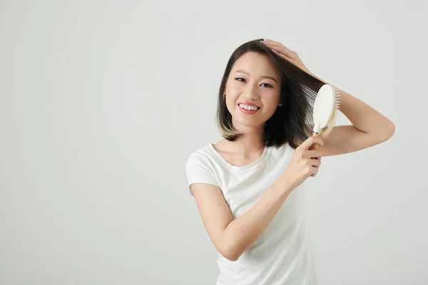 Студийный Портрет Радостной Молодой Женщины Расчесывающей Волосы Улыбающейся Перед Камерой — стоковое фото