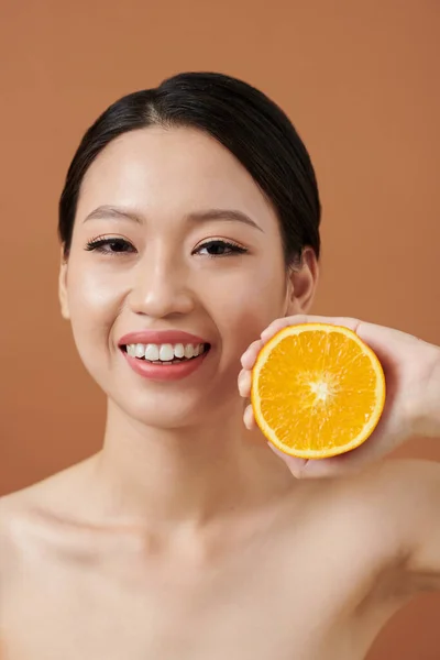 Portakalın Yarısını Tutan Kusursuz Ciltli Gülümseyen Genç Bir Kadının Portresi — Stok fotoğraf