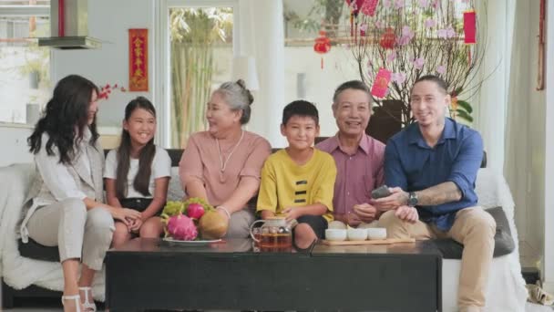 家で一緒に旧正月を祝いながら リビングルームでソファに座ってカメラに微笑む幸せなアジアの家族のグループの肖像画 — ストック動画