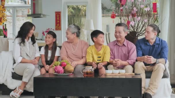 幸せな大規模なアジアの家族のリビングルームでソファに座って カメラを見て 家で旧正月を祝いながら願い事を言う — ストック動画
