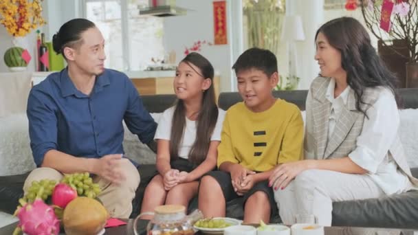 亚洲父母 儿子和女儿坐在家里装饰的沙发上 笑着聊天 — 图库视频影像