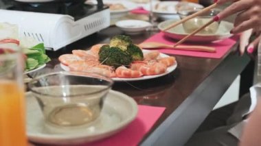 Tet 'te bayram yemeği yerken tahta çubuklarla karides yiyen bir kadının yakın plan fotoğrafları.