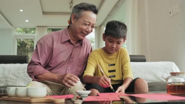 Senior Ázsiai Nagyapa Tanít Kisfiú Rajzolni Kalligráfia Miközben Kanapén Otthon — Stock videók
