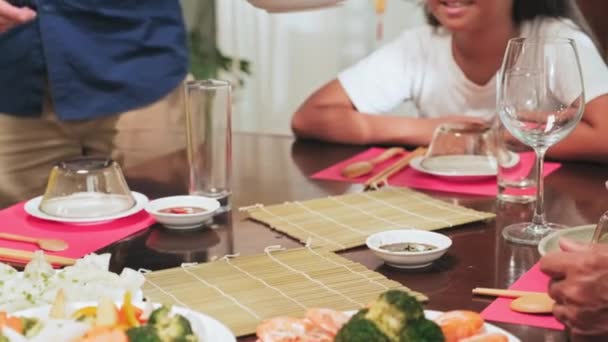 旧正月の休日の家族の夕食を持ちながら 子供のためのテーブルの上に伝統的なベトナム料理と2つの料理を提供する両親の作物のショット — ストック動画