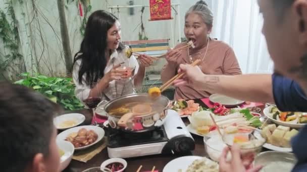 在节日期间 亚洲家庭围坐在餐桌旁 一边吃着火锅里的食物 一边靠肩膀拍照 — 图库视频影像