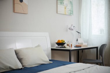 Huzurevinde yatağın yanında kitap ve meyvelerle dolu bir masa.