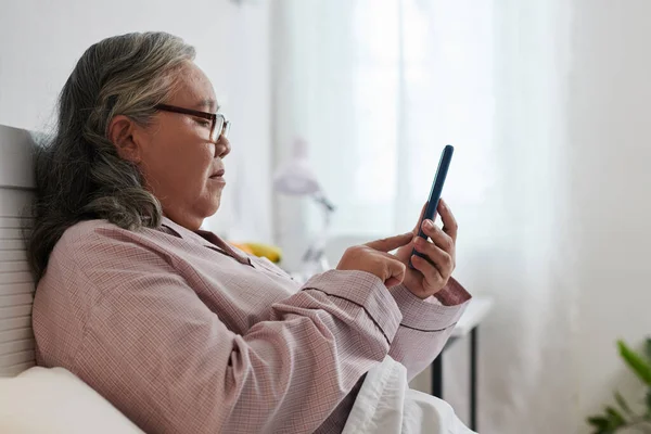 Seniorin Mit Brille Sitzt Bett Und Schreibt Freunden Oder Familienmitgliedern — Stockfoto