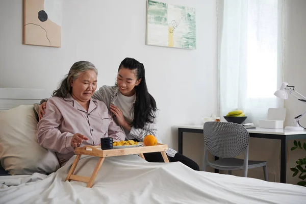 Smiling Granddaughter Bringing Tray Dinner Grandmother Sitting Bed — Stock Photo, Image