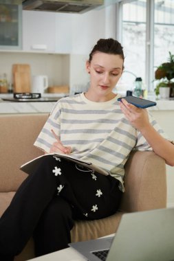 Ajandaya bakarken iş arkadaşı için sesli mesaj kaydeden genç bir kadın